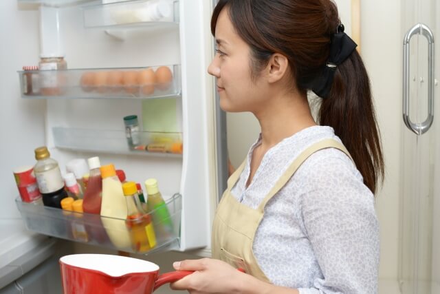 冷蔵庫を開けて食材を取り出す女性